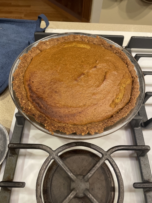 A pumpkin pie sitting on a stove